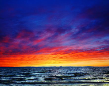 Beautiful colorful sunset over wavy waters, sea or ocean