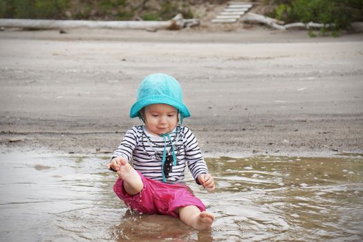 Desaturated shot of baby girl playing in the water at the beach