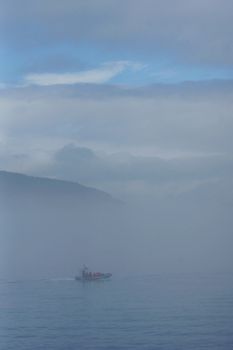 Inflatable boat with people on the St.Lawrence river on a very foggy day