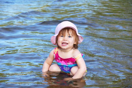Cute baby girl playing in the water of a lake