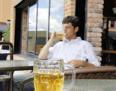 Young man drinking beer, focus on front glass bock