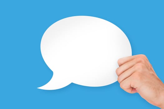 Human hand holding white, empty, blank speech bubble, isolated on blue background.