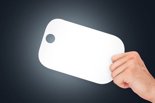 Hand holding white, empty, blank shopping label cardboard on dark background.
