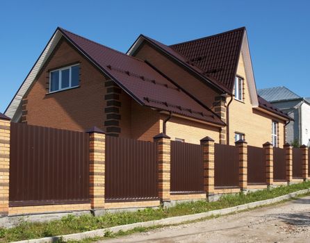 New country brick house behind a high metal fence