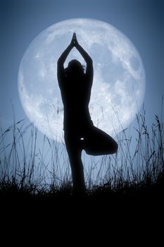 An image of a pretty woman doing yoga under a big pale moon