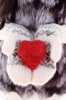 hands in woolen mittens holding red heart