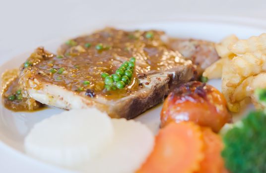 close up  beef  steak with green peppercorn sauce served with chips and vegetable