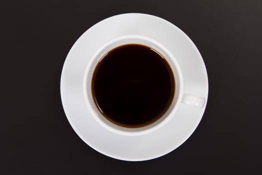 Black coffee in white ceramic cup, top view  on wooden table.