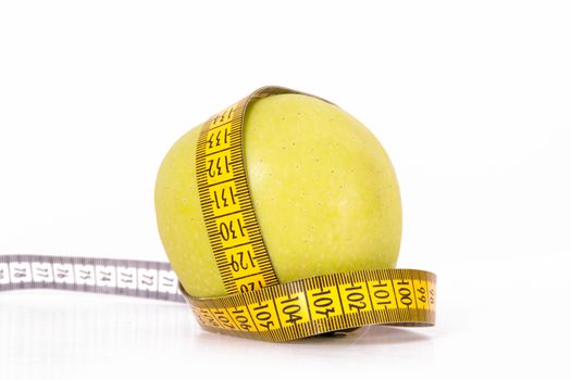 Green apples covered by yellow measure tape, isolated on white background.