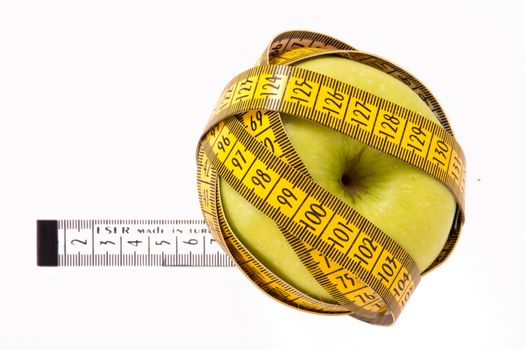 Green apples covered by yellow measure tape, isolated on white background.