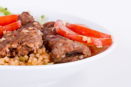 Baked Adana kebap, green salad with tomato, isolated on white.