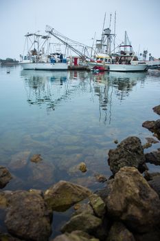 Fishing boats, yachts and dingys tied up at the harbor, ready to go to sea.