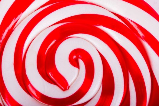 Red and white spiral lollipop candy as background.