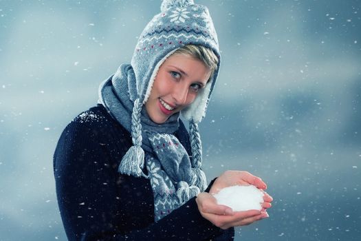 happy young woman presenting hand full of snow during snowfall