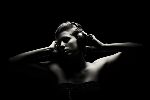 gorgeous woman in black and white tense light listening to music