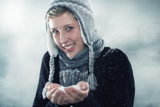 young happy woman wearing winter clothes showing a hand full of snow