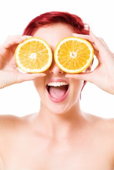 excited happy young redhead woman holding oranges over her eyes on white background