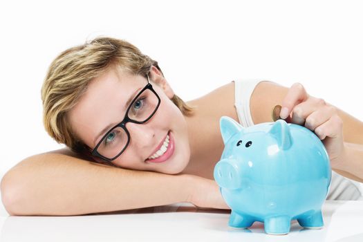 smiling woman throwing money in her piggy bank on white background