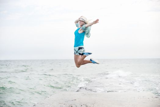 Happy young woman jumping on the beach