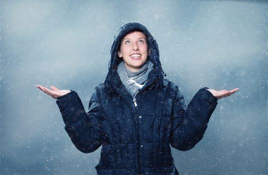 young woman is happy about snowfall looking up