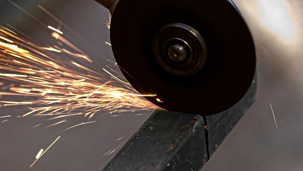 Metal sawing with hand grinder. Sparks while grinding iron.