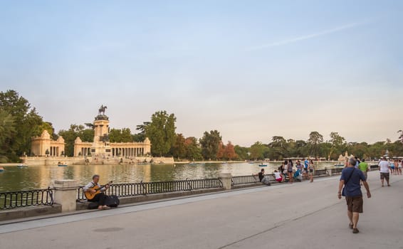 Madrid, Spain - September 02, 2013: People walking beside of Buen Retiro park lake, with monument to Alfonso XII on the background, in Madrid, Spain