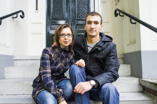 Portrait of love couple sitting on traditional Dutch porch looking happy