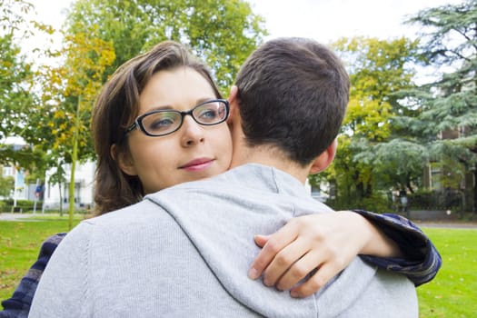 Portrait of love couple embracing outdoor in park looking happy