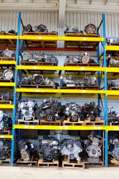 Car and truck engine block motors are lined up at an automobile salvage yard junkyard.