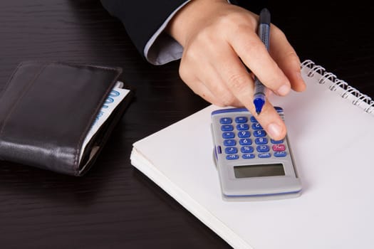 Business woman in suit calculating account on dark table.