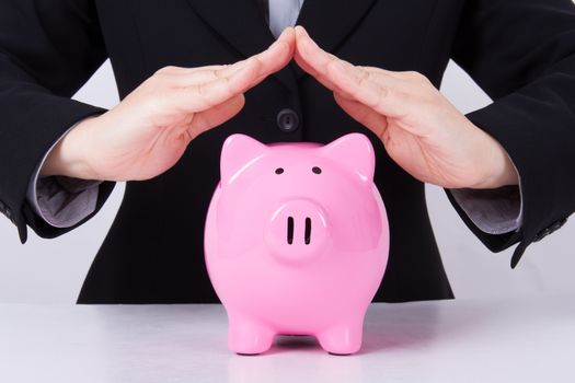 Business woman, roof shaped hands for estate, pink piggy bank.