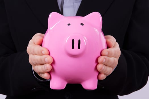 Business woman holding pink piggy bank between hands.