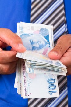 Businessman counting one hundred Turkish Lira banknotes.