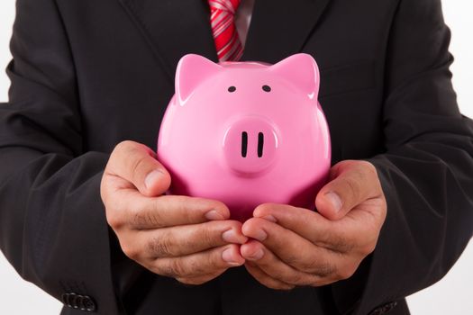 Businessman holding pink piggy bank, isolated on white background.