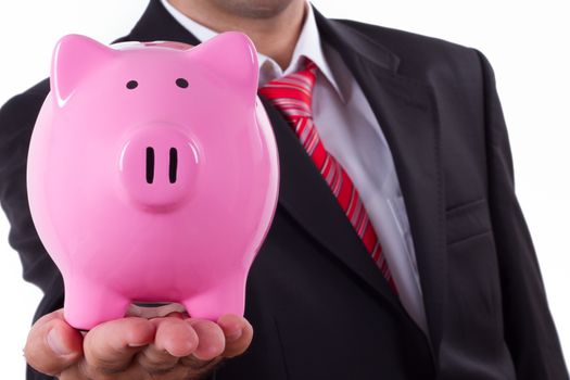 Businessman extends pink piggy bank, depth of field, isolated on white.