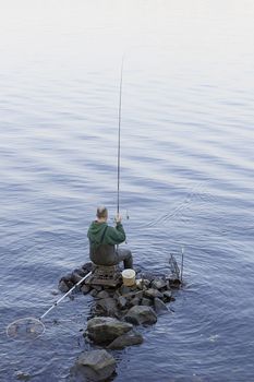 A fisherman with a fishing rod on the rocks.