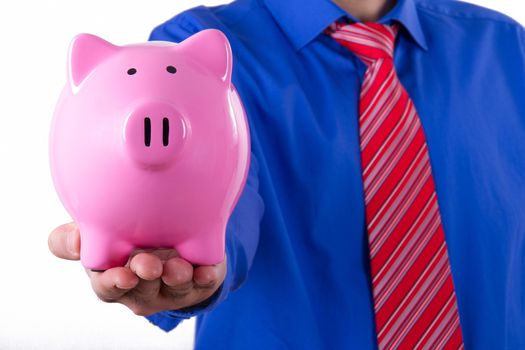 Businessman holding and showing pink piggy bank, isolated on white background.