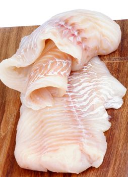 Two Slices of Raw Cod Fish Fillet closeup on Wooden Cutting Board on white background