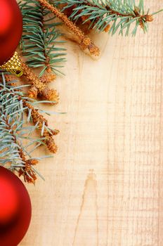 Corner Border of Green Spruce Branch with Fir Cones and Red Baubles closeup on Wooden background. Vertical View
