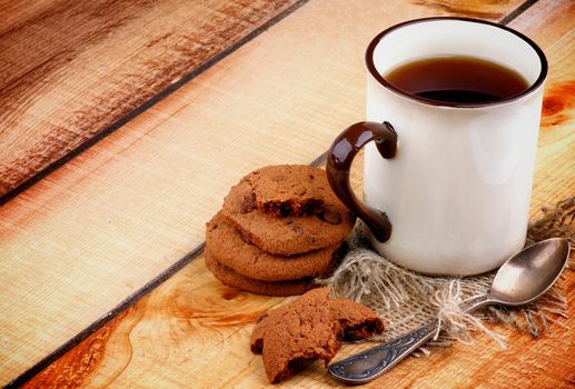 Rustic Cup of Black Tea with Chocolate Chip Cookies and Tea Spoon on Wooden background as Frame