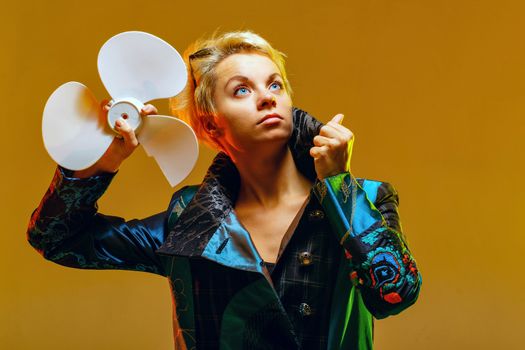 Girl in a jacket with a fan in hands, shot in the studio