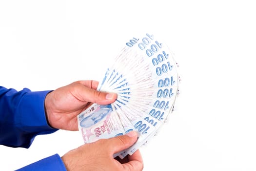 Businessman hand holding and counting one hundred Turkish liras banknotes, isolated on white background.