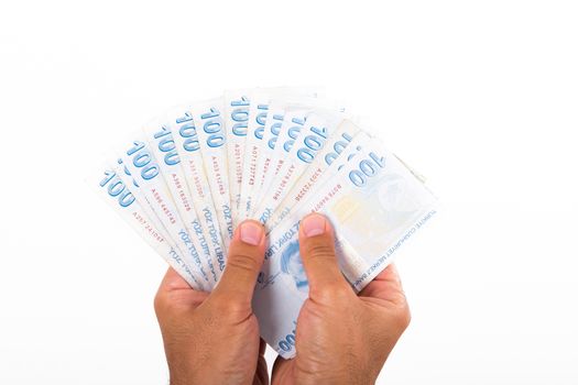Businessman hand holding and counting one hundred Turkish liras banknotes, isolated on white background.