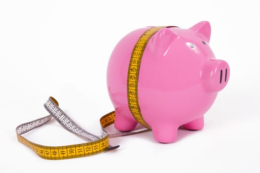 Measure tape and pink piggy bank, isolated on white background.