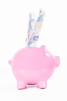 One hundred Turkish lira banknote in pink piggy bank, isolated on white background.