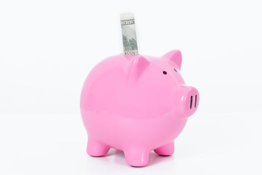 Pink piggy bank and one hundred dollar bill, isolated on white background.