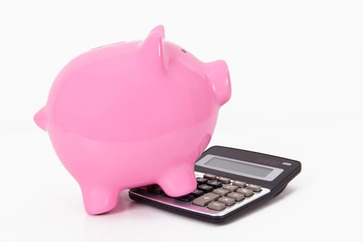 Pink piggy bank on calculator, isolated on white background.