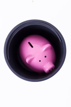 Pink piggy bank stacked in black bucket, top view, isolated on white background.