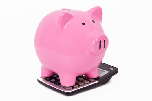 Pink piggy bank on calculator, isolated on white background.