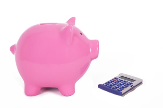 Pink piggy bank near calculator, isolated on white background.